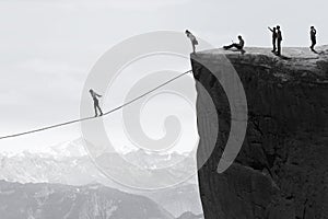 Businesspeople walking on the rope over the cliff