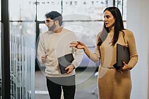 Businesspeople walking and talking in a bustling office, discussing projects and strategizing for profitability.