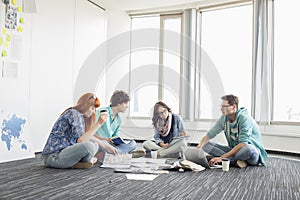 Businesspeople working on floor at creative work space