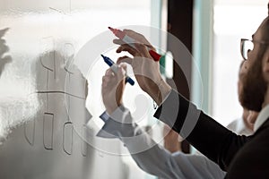 Businesspeople write on white board developing business plan together