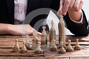 Businessperson Arranging Chess Piece On Stacked Coins