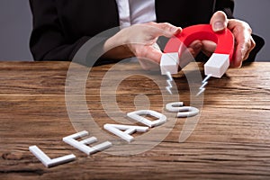 Businessperson Attracting Lead Text With Horseshoe Magnet