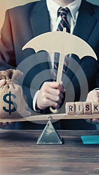 Businessperson balancing a money bag under an umbrella against wood blocks spelling RISK