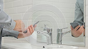 Businessperson in Bathroom Using His Mobile Phone Text Before Washing Hands