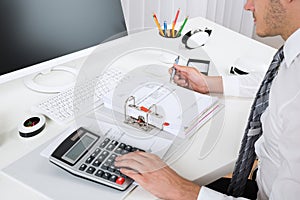 Businessperson Calculating Budget At Desk