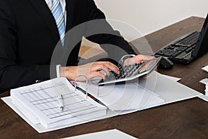 Businessperson Calculating Invoice In Office