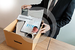 Businessperson carrying packing personal company on brown cardboard Box and resignation letters for quit or change of job leaving