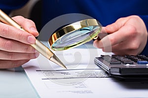 Businessperson Checking Bill Through Magnifying Glass