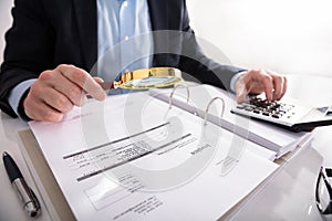 Businessperson Checking Invoice Through Magnifying Glass