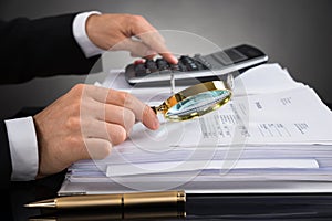 Businessperson Checking Invoice With Magnifying Glass