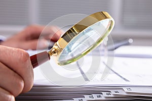 Businessperson Checking Invoice Through Magnifying Glass