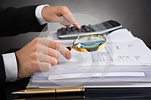 Businessperson Checking Invoice With Magnifying Glass