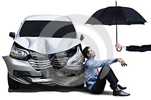 Businessperson with dented car and umbrella photo