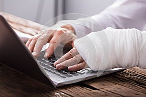 Businessperson With Hand Injury Using Laptop