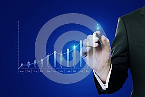 Businessperson hand pointing at glowing business chart on blue background. Invest and trade concept