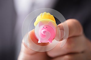 Businessperson Holding Piggybank With Hard Hat