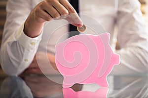 Businessperson Inserting Coin In Flat Piggybank