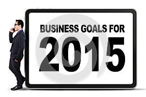 Businessperson leans on a business goals board
