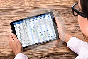 Businessperson Looking At Gantt Chart On Digital Tablet At Desk