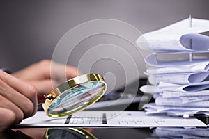 Businessperson Looking At Invoice Through Magnifying Glass