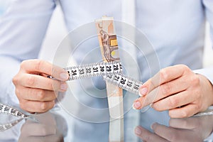 Businessperson with measuring tape and banknote