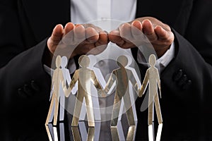 Businessperson Protecting Cut-out Figures photo