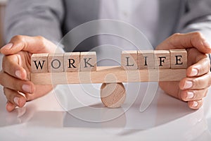 Businessperson Protecting Life And Work On Wooden Seesaw