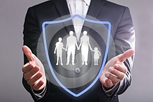 Businessperson`s Hand With Shield Protecting Family