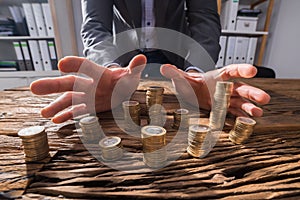 Businessperson`s Hand Surrounding Stack Of Coins