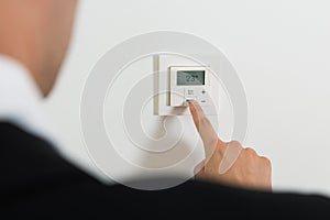 Businessperson Setting Temperature On Digital Thermostat