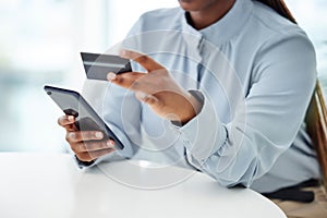 Businessperson using a credit card and phone to shop online at work. One person paying for a purchase using their