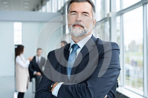 Businessteam in office, Happy Senior Businessman in His Office is standing in front of their team.
