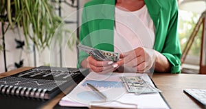 Businesswoman or accountant counting dollar bill at workplace