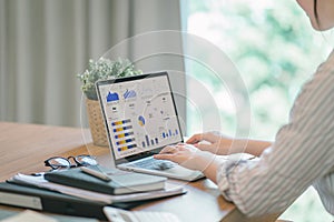 Businesswoman accountant using a calculator, graphs, and charts to analyze market data, balance sheets,accounts,and net