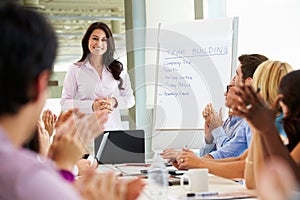 Businesswoman Addressing Meeting Around Boardroom Table