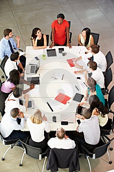 Businesswoman Addressing Meeting Around Boardroom Table