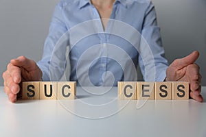 Businesswoman adjusting `success` word made of wooden blocks. Success word from wooden blocks on desk. Business success