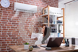 Businesswoman Adjusting The Temperature Of Air Conditioner