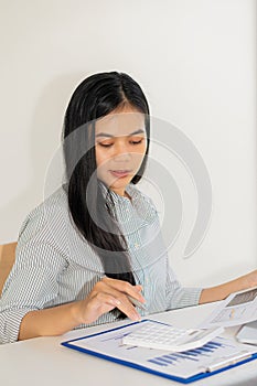 Businesswoman analyzing and brainstorming data, charts, financial reports in the office with laptop and calculator. Ideas for work