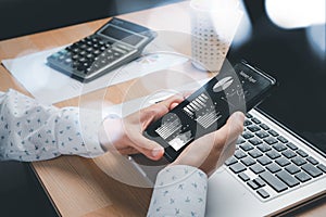 Businesswoman analyzing financial data on smartphone and computer screen