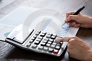 Businesswoman Analyzing Financial Report With Calculator