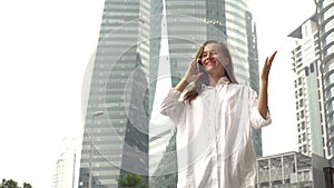 Businesswoman answer phone, receive good news, excited happy cheerful. Victory gesture. Business district skyscrapers in