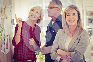 Businesswoman with arms crossed with her team behind