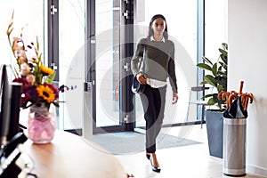 Businesswoman Arriving For Work At Office Walking Through Door