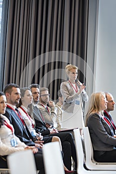 Businesswoman asking questions during seminar in convention center