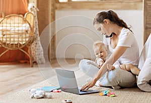 Businesswoman with baby boy working from home using laptop, phone