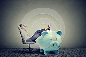 Businesswoman with big piggy bank relaxing sitting on chair