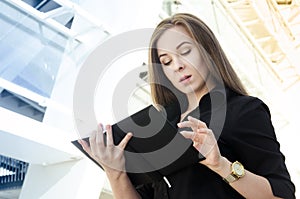 businesswoman in black clothes with long hair flips a black notebook