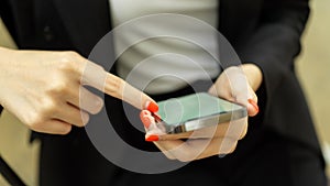 Businesswoman in black suit hands using smartphone, index finger touching on phone screen