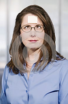 Businesswoman with a blank note on her forehead